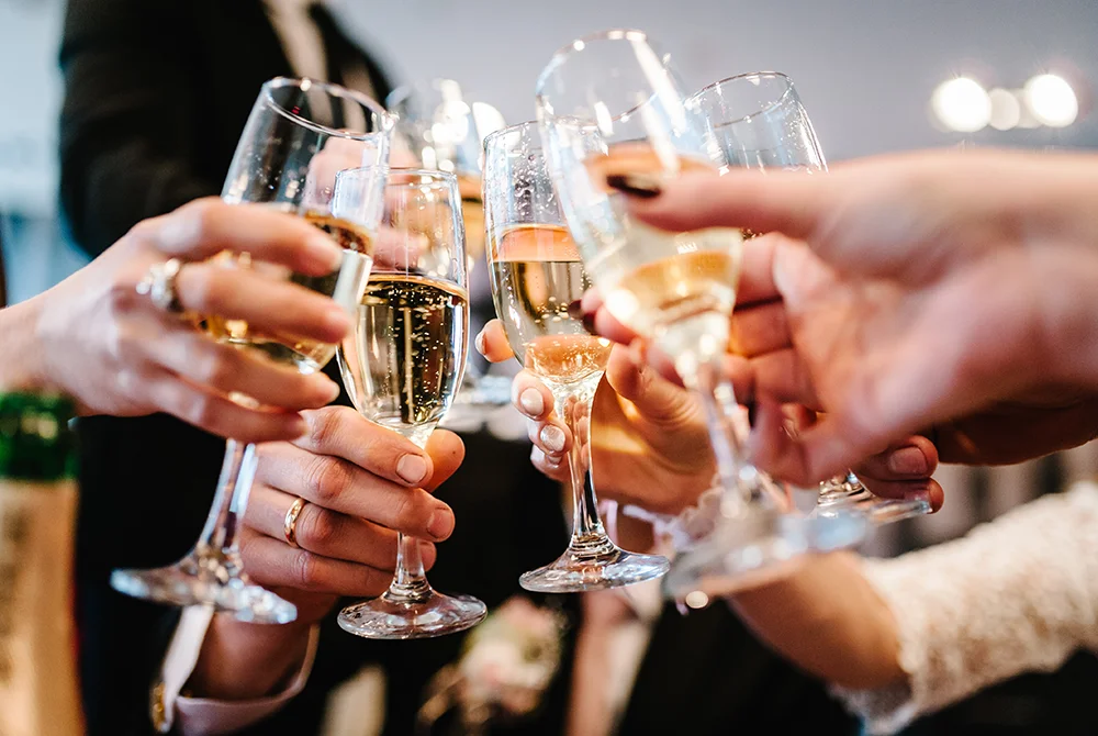 A group of people clinks their champagne glasses together in a celebratory toast, with hands and sparkling drinks in focus, capturing the essence of fine dining in Greenville, ME.